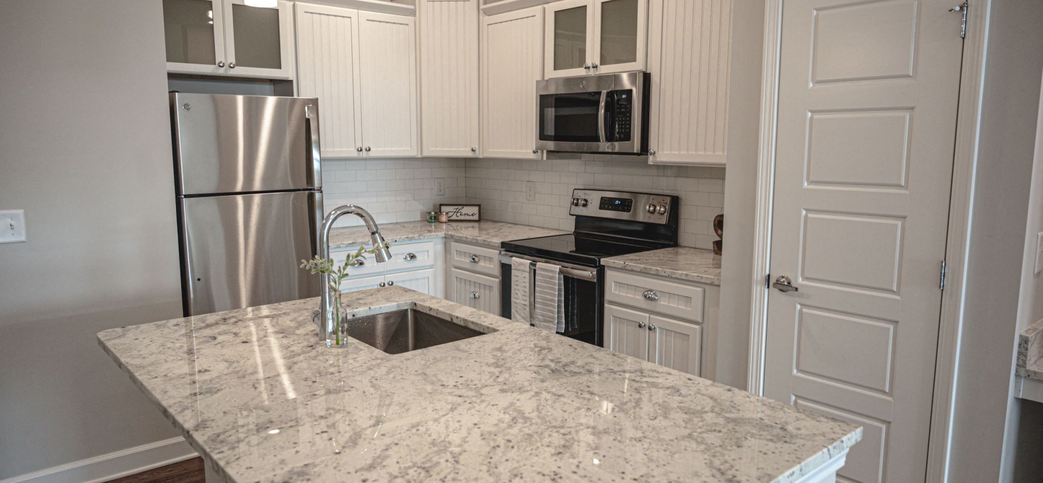 Hawthorne at Smith Creek apartment kitchen interior with granite kitchen island, stainless steel appliances, and white cabinetry